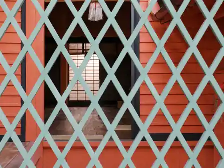 Pale green diamond lattice before vermilion timber walls and a softly lit shoji screen