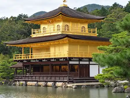 The gold upper floors and dark wooden lower floor of Kinkaku-ji beside a pond, partly framed by pine branches.
