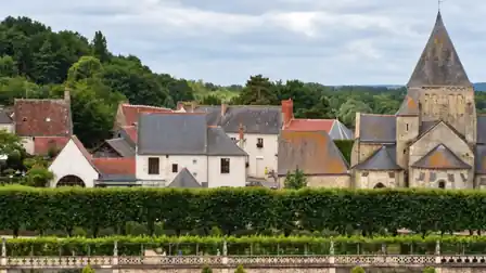 The roofs of Villandry village and the stone tower and apse of Saint-Étienne church above clipped garden hedges.